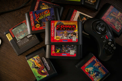 Cartuchos de jogos retro espalhados numa mesa de madeira, com um comando de consola antiga