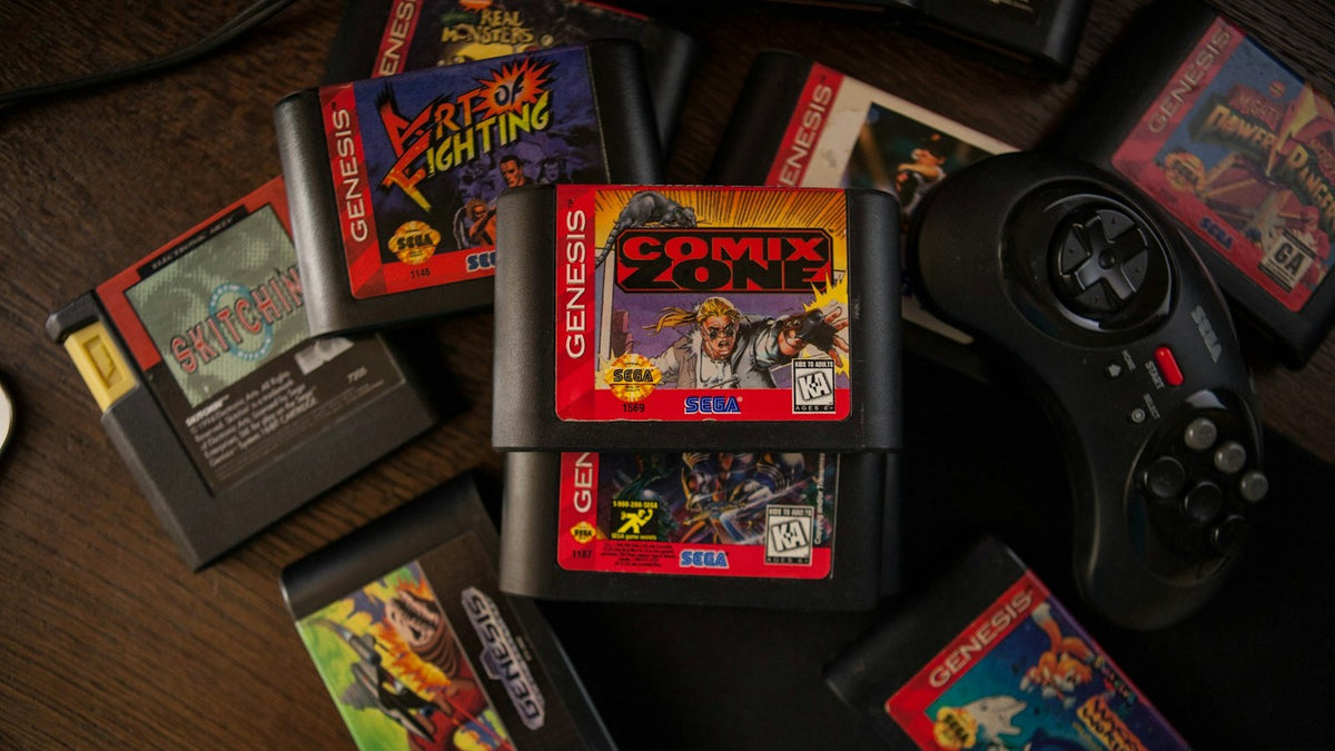 Cartuchos de jogos retro espalhados numa mesa de madeira, com um comando de consola antiga