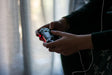 Mãos a segurar um comando de videojogos numa sala escura, simbolizando as horas passadas a jogar videojogos