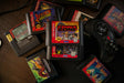 Cartuchos de jogos retro espalhados numa mesa de madeira, com um comando de consola antiga