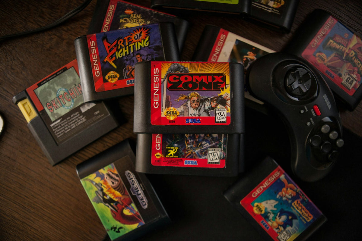 Cartuchos de jogos retro espalhados numa mesa de madeira, com um comando de consola antiga